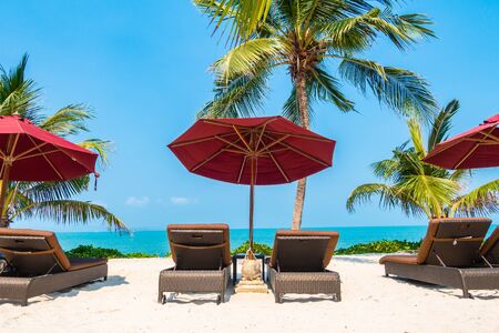 Beautiful tropical beach sea ocean with umbrella and chair around coconut palm tree on blue sky for...
