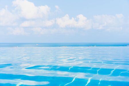 Beautiful infinity outdoor swimming pool with sea ocean view around white cloud blue sky for leisure...