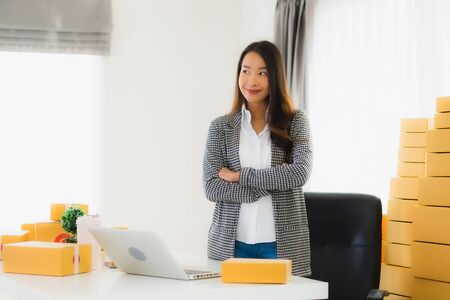 Portrait beautiful young asian business woman work from home with laptop mobile phone with cardboard...