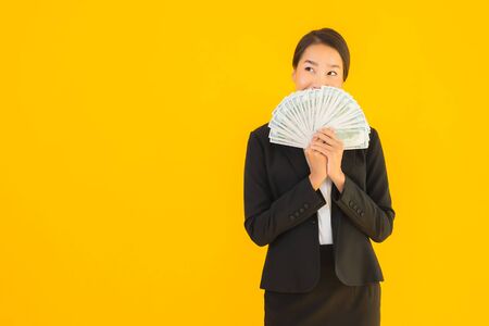 Beautiful portrait young asian woman with a lot of monet cash on yellow isolated backgroundの写真素材