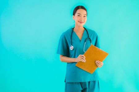Portrait beautiful young asian doctor woman with empty paper board for copy space on blue isolated background - Healthcare in hospital and clinic conceptの写真素材