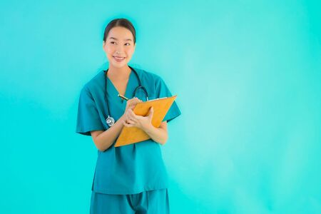 Portrait beautiful young asian doctor woman with empty paper board for copy space on blue isolated background - Healthcare in hospital and clinic conceptの写真素材