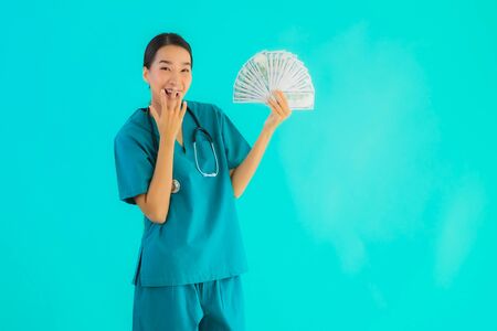 Portrait beautiful young asian doctor woman show money and cash on blue isolated backgroundの写真素材