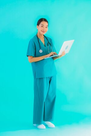 Portrait beautiful young asian doctor woman with laptop or computer on blue isolated backgroundの写真素材