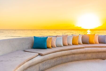Comfortable pillow on sofa chair around outdoor patio with sea ocean beach view for travel vacation at sunriseの写真素材