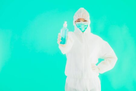 Portrait beautiful young asian doctor woman wear ppe suite and mask with alcohol gel on blue...