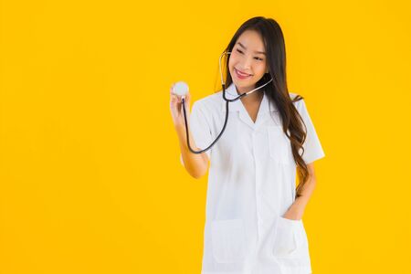 Portrait beautiful young asian doctor woman smile happy work in hospital and clinic on yellow isolated backgroundの写真素材