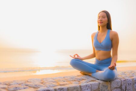 Portrait young asian woman do meditation around sea beach ocean at sunrise for healthの写真素材