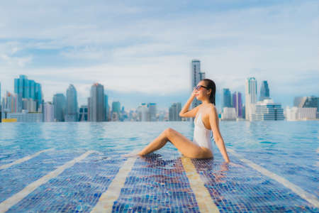 Portrait beautiful young asian woman relax happy smile leisure around outdoor swimming pool with cityscapeの写真素材