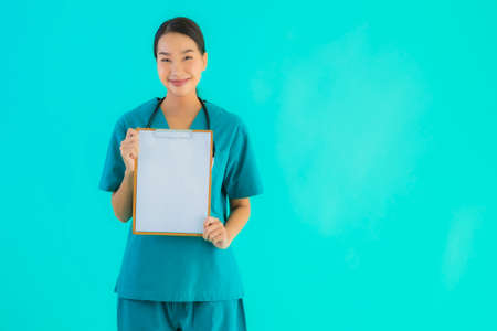 Portrait beautiful young asian doctor woman with empty paper board for copy space on blue isolated background - Healthcare in hospital and clinic conceptの写真素材