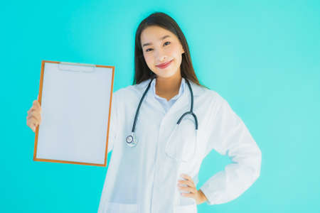 Portrait beautiful young asian doctor woman with empty card billboard banner on blue isolated backgroundの写真素材