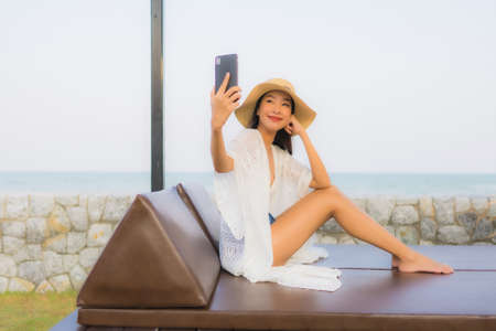 Portrait young asian woman using smart mobile phone around outdoor beach sea oceanの写真素材