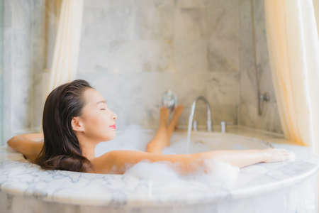 Portrait of beautiful young asian woman relaxing inside a bathtubの写真素材
