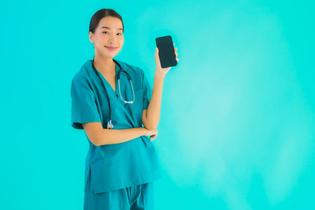 Portrait beautiful young asian doctor woman show smart mobile phone on blue isolated backgroundの写真素材