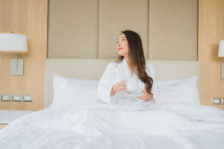 Portrait beautiful young asian woman smile happy relax and leisure on bed in bedroom interior