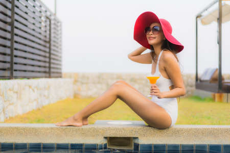 Portrait beautiful young asian woman relax around outdoor swimming pool in hotel resort with palm...
