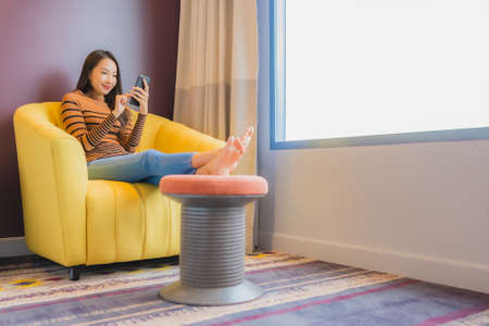Portrait beautiful young asian woman relax smile in action on sofa in living room interior