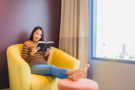 Portrait beautiful young asian woman relax smile in action on sofa in living room interior
