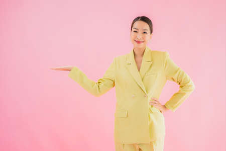 Portrait beautiful young asian business woman smile in action on pink color backgroundの写真素材