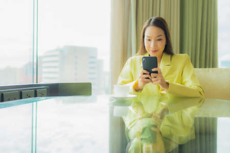 Portrait beautiful young asian woman with smart mobile phone on brown background