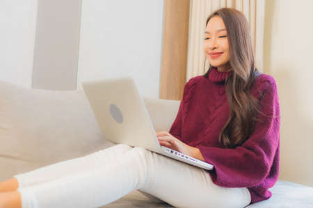 Portrait beautiful young asian woman smile relax on sofa in living room interior