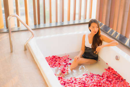 Portrait beautiful young asian woman with coffee cup and mobile phone on bed in bedroom interior