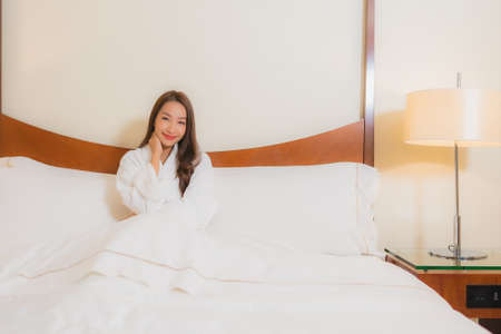 Portrait beautiful young asian woman smile relax leisure on bed in bedroom interiorの写真素材