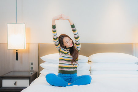 Portrait beautiful young asian woman smile happy relax on bed in bedroom interiorの写真素材