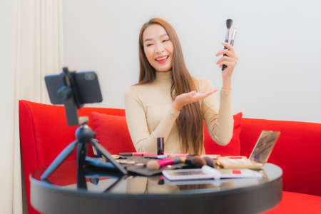Portrait young asian woman using laptop computer with smart mobile phone and credit card for online shopping in living roomの写真素材