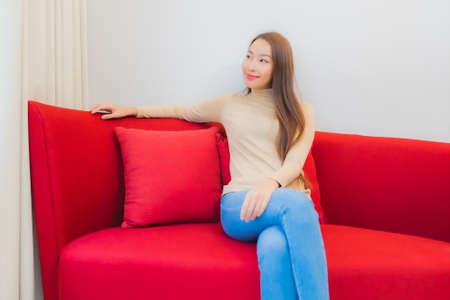 Portrait beautiful young asian woman smile relax on sofa in living room interiorの写真素材