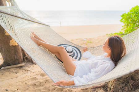 Portrait beautiful young asian woman relax smile leisure on swing around beach sea ocean with blue sky white cloudの写真素材