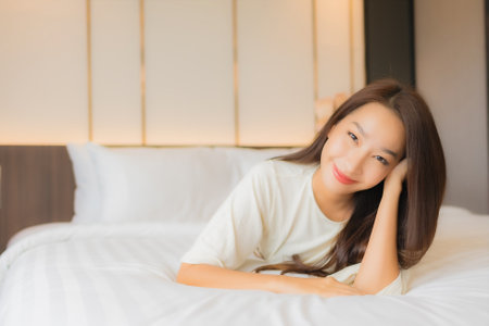 Portrait beautiful young asian woman smile relax leisure on bed in bedroom interiorの写真素材