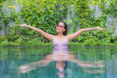 Portrait beautiful young asian woman relax smile around outdoor swimming pool in hotel resort nearly sea beach oceanの写真素材
