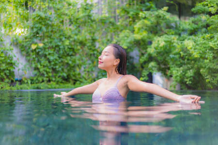 Portrait beautiful young asian woman relax smile around outdoor swimming pool in hotel resort nearly...