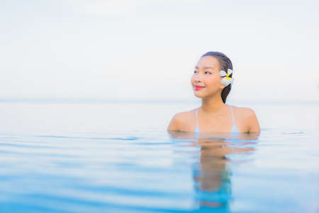 Portrait beautiful young asian woman relax smile around outdoor swimming pool in hotel resort nearly sea beach oceanの写真素材
