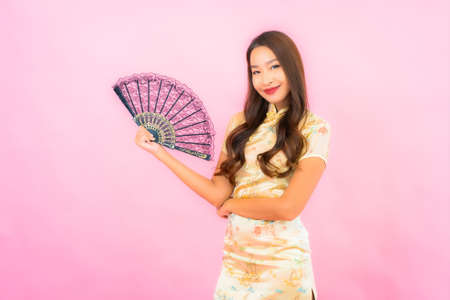 Portrait beautiful young asian woman with chinese new year concept and fan on color backgroundの写真素材