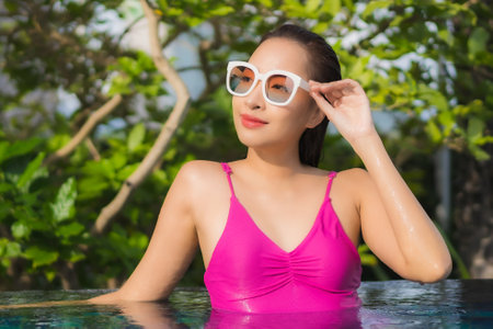 Portrait beautiful young asian woman with mask and smart mobile phone or cellphone on yellow isolated backgroundの写真素材