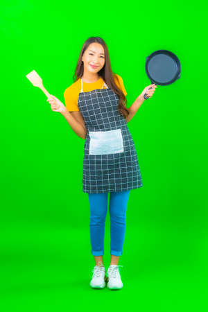 Portrait beautiful young asian woman wear apron with action on green isolated backgroundの写真素材