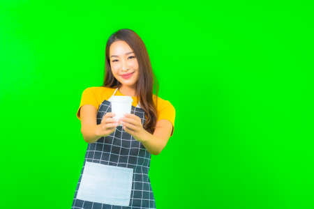 Portrait beautiful young asian woman wear apron with action on green isolated backgroundの写真素材