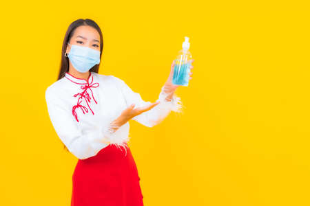 Portrait beautiful young asian woman chef wear mask for protect covid19 or coronavirus on yellow isolated backgroundの写真素材