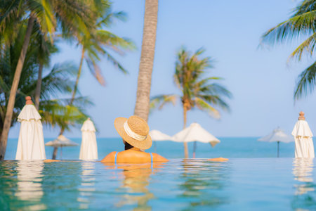 Portrait beautiful young asian woman relax smile enjoy leisure around swimming pool nearly sea beach ocean view for leisure vacationの写真素材