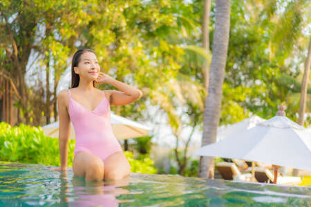 Portrait beautiful young asian woman relax smile enjoy leisure around swimming pool in hotel resortの写真素材
