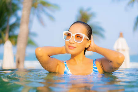 Portrait beautiful young asian woman relax smile enjoy leisure around swimming pool in hotel resort