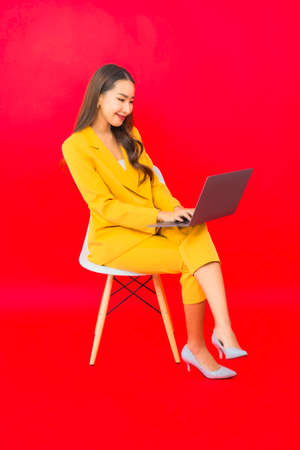 Portrait beautiful young asian woman use mobile with credit card on red backgroundの写真素材