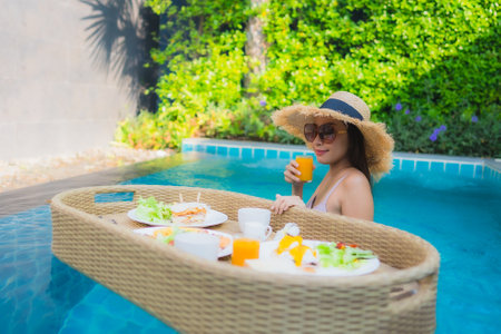 Portrait beautiful young asian woman smile relax around outdoor swimming pool in resort hotel on holiday vacation travel tripの写真素材