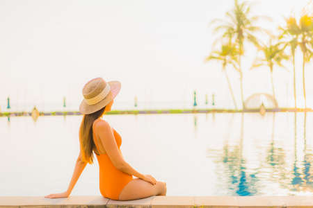 Portrait beautiful young asian woman relax smile leisure around outdoor swimming pool with sea ocean in travel vacationの写真素材