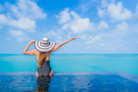 Portrait beautiful young asian woman relax smile leisure around outdoor swimming pool in resort hotel with sea ocean viewの写真素材