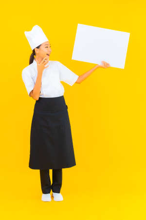 Portrait beautiful young asian woman show white empty billboard on yellow isolated backgroundの写真素材