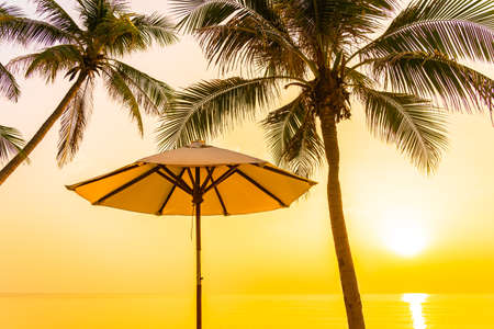 Umbrella and deck chair around beach sea ocean with coconut palm tree at sunset or sunrise for leisure vacationの写真素材
