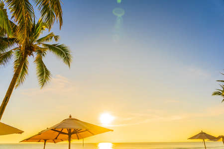 Beautiful tropical nature umbrella chair with palm tree around beach sea ocean at sunset or sunrise for travel vacationの写真素材